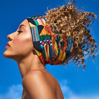 Woman in profile against a blue sky wearing the Multi-Use Beauty Band as a wide headband, with her curls gathered up behind it