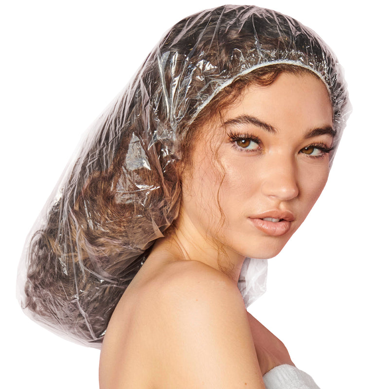 Woman with long, curly hair wearing an oversized clear processing cap that covers all of her hair past her shoulders