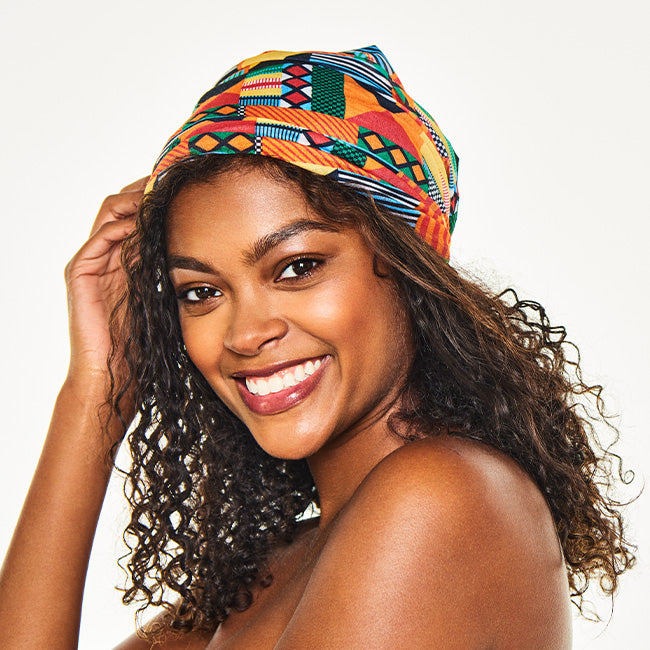 Smiling woman wearing the Multi-Use Beauty Band as a head wrap, with her curly hair down