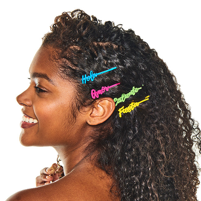 Smiling woman with curly hair wearing all four Atrevida barrettes stacked at the side of her head