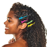 Smiling woman with curly hair wearing all four Atrevida barrettes stacked at the side of her head
