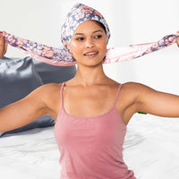 Woman bringing the ties of the floral wrap cap to the top of her head to knot them