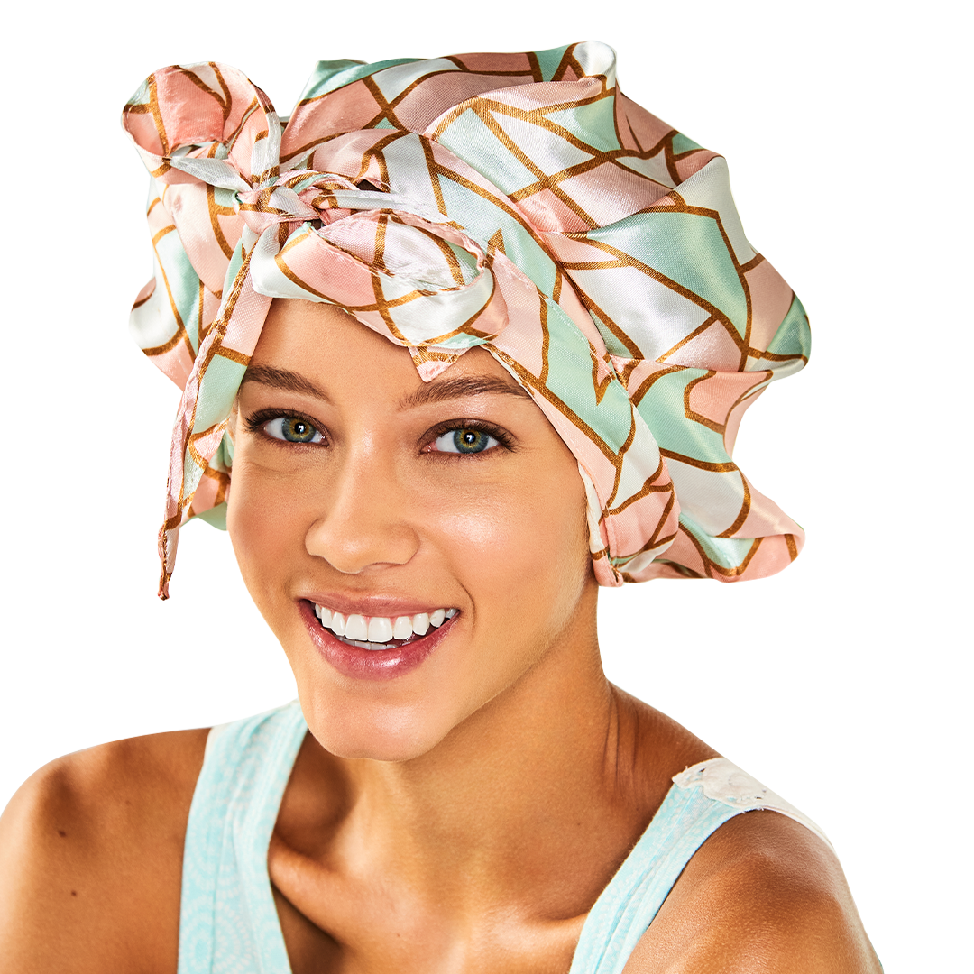 Smiling woman wearing the Adjustable Satin Bonnet with the ties knotted in a bow on top
