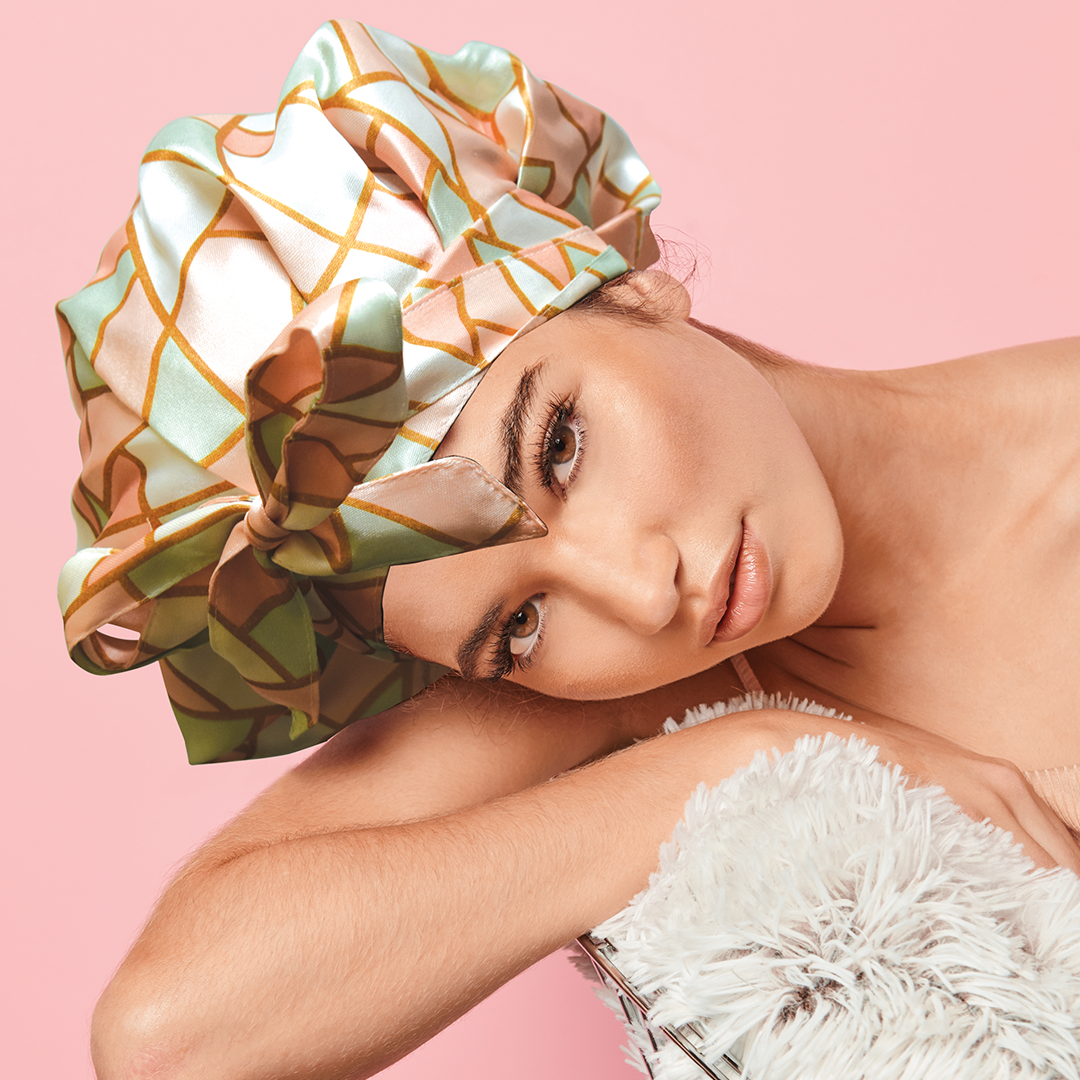 Woman resting her head on a fluffy pillow, wearing the Adjustable Satin Bonnet