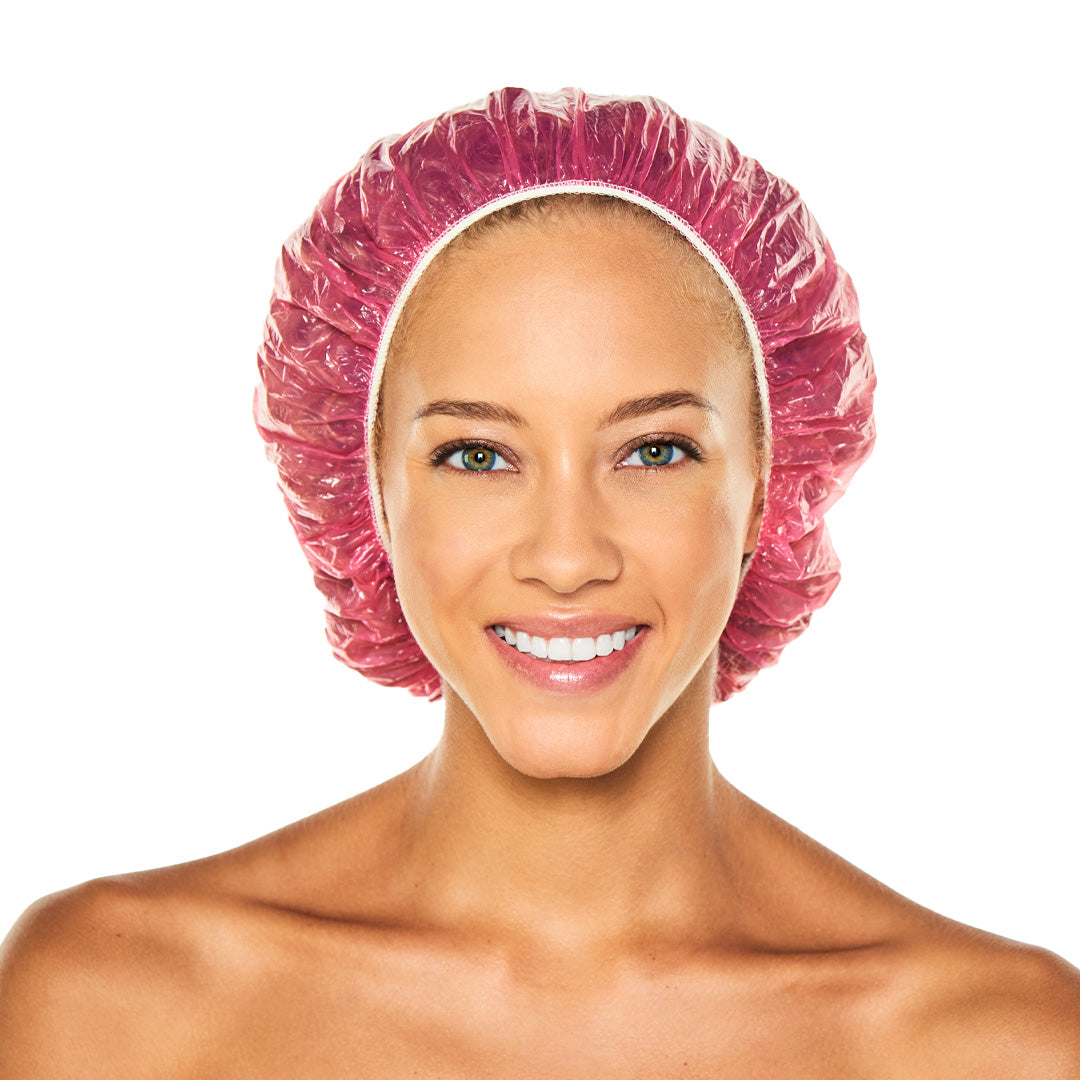 Smiling woman wearing a pink disposable shower cap with white elastic trim