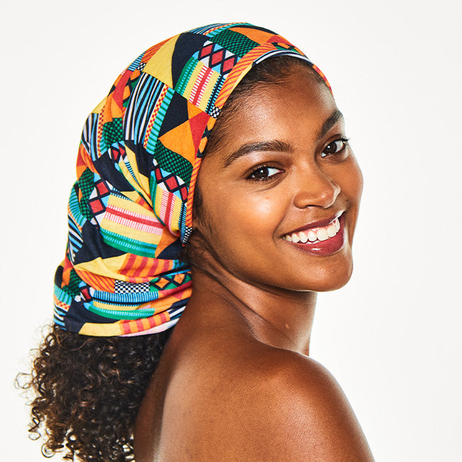 Smiling woman looking over her shoulder, wearing the Multi-Use Beauty Band as a head scarf covering her hair