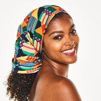 Smiling woman looking over her shoulder, wearing the Multi-Use Beauty Band as a head scarf covering her hair